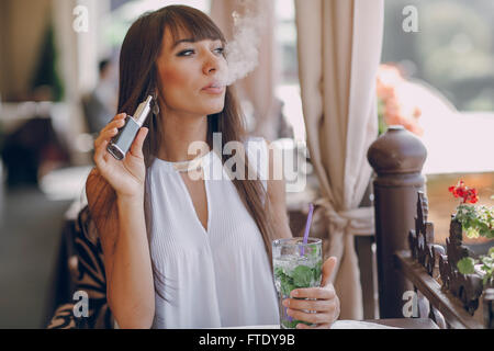 Girn in cafe con E-sigaretta Foto Stock