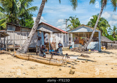 La gente del luogo di relax all'ombra nei pressi di legno tradizionale piroga con buttafuori Foto Stock