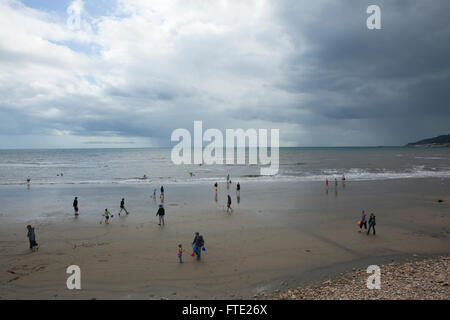 Vacanze a piedi e giocando sulla sabbia di una spiaggia britannico in una scena di tipico british estate meteo, umido e nuvoloso con una mancanza di sole. Foto Stock