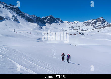 Due maschi escursionisti con racchette da neve escursioni su una soleggiata giornata invernale nelle Alpi Svizzere. Melchsee-Frutt, Cantone di Obvaldo, Svizzera. Foto Stock