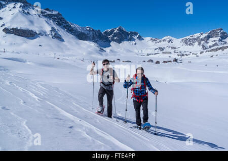 Due maschi escursionisti con racchette da neve escursioni su una soleggiata giornata invernale nelle Alpi Svizzere. Melchsee-Frutt, Cantone di Obvaldo, Svizzera. Foto Stock