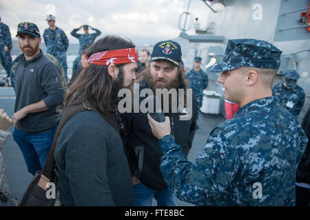 SOUDA BAY, Grecia (dec. n. 07, 2013) - comunicazione di massa Specialist Seaman Joshua Fulton interviste 'Duck Dynasty' stelle Jep, sinistra e Willie Robertson durante un tour del Arleigh Burke-class guidato-missile destroyer USS Stout (DDG 55). Il tour è parte dell'annuale OSU tour vacanza, che dispone di una varietà di altre celebrità e il Presidente del Comune di capi di Stato Maggiore visitando le basi e le navi a interagire con l'equipaggio per le vacanze. Stout, homeported a Norfolk, Virginia, è su una distribuzione programmata sostenere le operazioni di sicurezza marittima e di teatro di sicurezza gli sforzi di cooperazione in Foto Stock