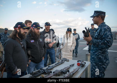 SOUDA BAY, Grecia (dec. n. 07, 2013) - Da bombardieri Mate 2a classe Gregorio Spaulding siete mostra 'Duck Dynasty' stelle Jep, sinistra e Willie Robertson le armi che la Arleigh Burke-class guidato-missile destroyer USS Stout (DDG 55) presenta sul bordo. La dimostrazione è parte dell'annuale OSU tour vacanza, che dispone di una varietà di altre celebrità e il Presidente del Comune di capi di Stato Maggiore visitando le basi e le navi a interagire con l'equipaggio per le vacanze. Stout, homeported a Norfolk, Virginia, è su una distribuzione programmata sostenere le operazioni di sicurezza marittima e di teatro la cooperazione in materia di sicurezza FEP Foto Stock