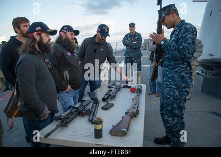 SOUDA BAY, Grecia (dec. n. 07, 2013) - Da bombardieri Mate 2a classe Gregorio Spaulding siete mostra 'Duck Dynasty' stelle Jep e Willie Robertson, e Washington cittadini giocatore di baseball Adam Laroche, le armi che la Arleigh Burke-class guidato-missile destroyer USS Stout (DDG 55) presenta sul bordo. La dimostrazione è parte dell'annuale OSU tour vacanza, che dispone di una varietà di altre celebrità e il Presidente del Comune di capi di Stato Maggiore visitando le basi e le navi a interagire con l'equipaggio per le vacanze. Stout, homeported a Norfolk, Virginia, è su una distribuzione programmata supporto securit marittima Foto Stock