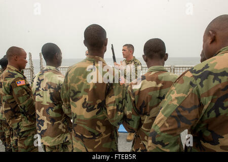 140305-N-ZY039-350 Monrovia, Liberia (7 marzo 2014) - Chief Master-at-Arms Bryan Roelike, un membro della sicurezza imbarcato a bordo del team joint ad alta velocità a nave USNS Spearhead (JHSV 1), spiega equipaggio servito armi ai membri della Liberia Guardia Costiera durante un giunto di familiarizzazione di esercitare sulla nave. Punta di diamante. Punta di diamante, U.S. Navy's first-in-class, comune ad alta velocità a vaso, è sulla sua fanciulla distribuzione teatro di supporto di sicurezza gli sforzi di cooperazione e collaborazione internazionali di programma per il potenziamento delle capacità, Africa Partnership Stazione, NEGLI STATI UNITI Sesta flotta area di operazioni. (Brevetto statunitense n. Foto Stock