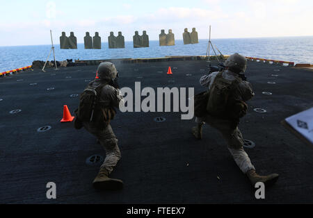 Questa immagine cattura due cannonieri della 22nd Marine Expeditionary Unit che si scontrano con obiettivi durante un raggio di fuoco vivo a bordo della USS Bataan nel 2014, dimostrando prontezza al combattimento e addestramento. Foto Stock