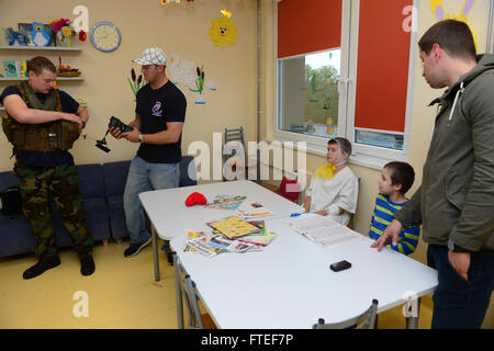 Questa foto del 29 giugno 2014 mostra il personale della Marina degli Stati Uniti a bordo della USS Oscar Austin, che visita un ospedale pediatrico a riga, in Lettonia. I marinai, l'Aircrewman Brendon Mulholland e l'Aircrew Survival Equipmentman Michael Haines, si stanno impegnando con i bambini locali e stanno mostrando l'equipaggiamento dell'equipaggio come parte di uno sforzo di sensibilizzazione della comunità durante il loro dispiegamento. Foto Stock