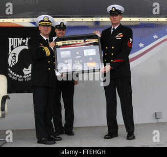 CMdR. Scott Jones, comandante della USS Donald Cook (DDG 75), riceve un dono dall'equipaggio durante una cerimonia di cambio di comando il 17 ottobre 2014, presso la Naval Station di Rota, in Spagna. Il cacciatorpediniere fa parte del dispiegamento strategico della Marina degli Stati Uniti in Europa. Foto Stock