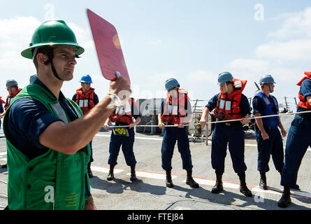 Mare Mediterraneo (Agosto 18, 2013) Ð Cryptologic tecnico (tecnico) 2a classe Benjamin Kieldhold, da Sioux City, Iowa, segnali per ricevere la linea durante un rifornimento verticale in mare (VERTREP) con militare Sealift oliatore comando USNS Leroy Grumman (T-AO 195) a bordo del missile destroyer USS gravemente (DDG 107). Gravemente, homeported a Norfolk, Virginia, è su una distribuzione programmata sostenere le operazioni di sicurezza marittima e di teatro la cooperazione in materia di sicurezza gli sforzi nella sesta flotta area di responsabilità. Foto Stock