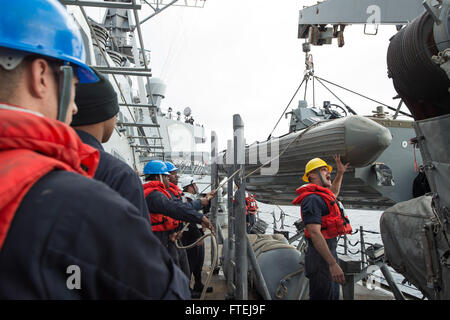 Mare Mediterraneo (nov. 15, 2014) - di Boatswain Mate 2a classe Alan Farthing, da Grove City, Ohio, dà istruzioni ai gestori di linea come egli controlla un rilievo-gonfiabile dello scafo della barca entrobordo swing durante una barca di operazione di recupero a bordo della USS Cole (DDG 67). Cole, un Arleigh Burke-class guidato-missile destroyer homeported in Norfolk, sta conducendo operazioni navali negli Stati Uniti Sesta flotta area di operazioni a sostegno degli Stati Uniti per gli interessi di sicurezza nazionali in Europa. Foto Stock