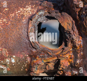 Un tubo di metallo che ha completamente arrugginiti, con un foro visibile Foto Stock