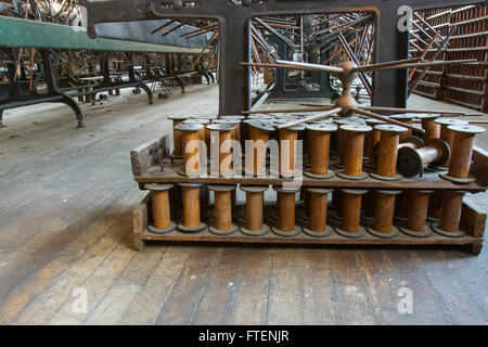Vuoto gli steli di legno sul pavimento della fine del secolo la seta gettando fabbrica con attrezzature di antiquariato. Foto Stock