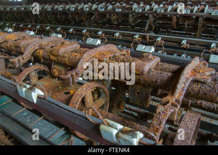 Arrugginimento macchinari abbandonati in giro del secolo la seta gettando fabbrica. Foto Stock