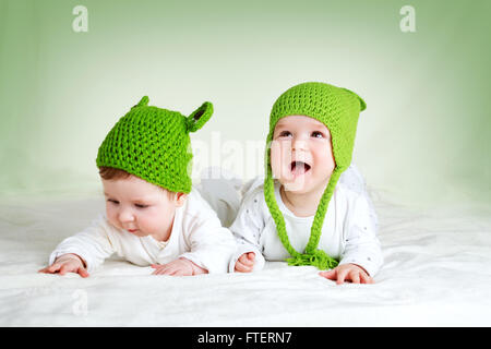 Due graziosi bambini giacente in cappelli di rana su spft coperta Foto Stock