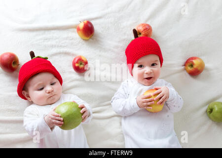 Due graziosi bambini giacente in cappelli sul morbido manto con mele Foto Stock