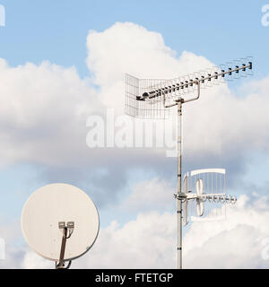 Antenna TV e satellite dish contro un cielo blu Foto Stock