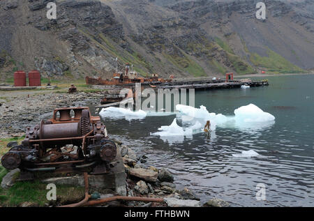 Una caccia alla balena spiaggiata barca, altri macchinari, dei serbatoi di stoccaggio e il ghiaccio sulla spiaggia nelle rovine di Grytviken stazione baleniera. Foto Stock