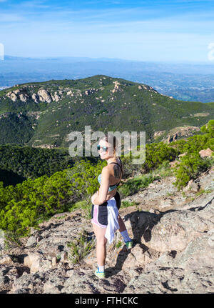 Escursionista sul picco di arenaria a cerchio X Ranch, con equilibrata Rock visto in distanza Foto Stock