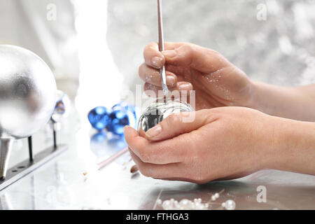 Pittura palle di Natale. Fabbricazione e artigianato. Donna decorare baubles. Addobbi per l'albero di natale Foto Stock