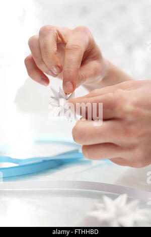 Le mani di donne costituiti da carta decorazioni natalizie. Carta Origami star stelle scheda di Natale con le strisce di carta Foto Stock