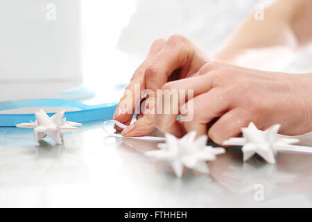Le mani di donne costituiti da carta decorazioni natalizie. Carta Origami star stelle scheda di Natale con le strisce di carta Foto Stock