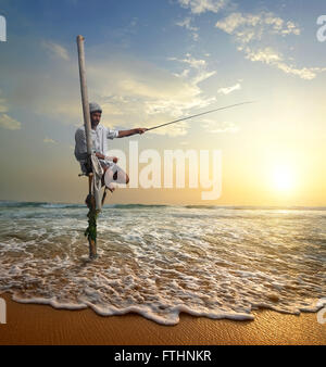 Pescatore locale su stick su una spiaggia dell'oceano indiano, Sri Lanka Foto Stock