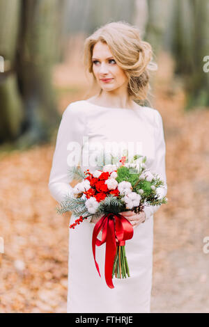 Ritratto di bella bionda sposa con bouquet di nozze in posa la foresta di autunno Foto Stock