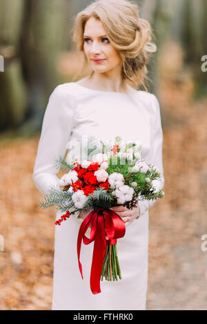 Giovane bella bionda elegante sposa con bouquet nella foresta di autunno Foto Stock