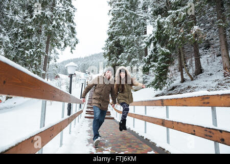 Emozionato allegro coppia giovane saltando e correndo insieme in inverno Foto Stock
