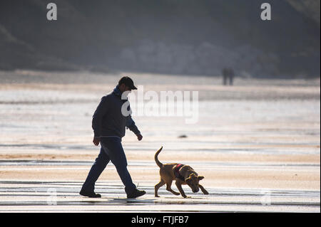 Un uomo e il suo cane che godono di una buona passeggiata sulla Fistral Beach in Newquay, Cornwall. Foto Stock