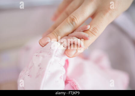 Madre del dito tenendo la mano per neonati Foto Stock