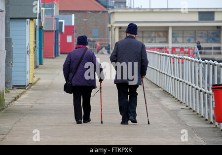 Coppia di anziani a piedi sul lungomare a Sheringham, North Norfolk, Inghilterra Foto Stock