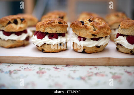 Focaccine di frutta con panna e lampone ripieno su una tavola di legno su una tovaglia floreale in una panetteria Foto Stock