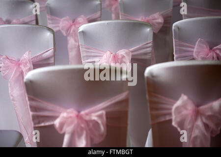 Coperta bianca sedia nozze dorsi con nastro rosa infissi e archi Foto Stock