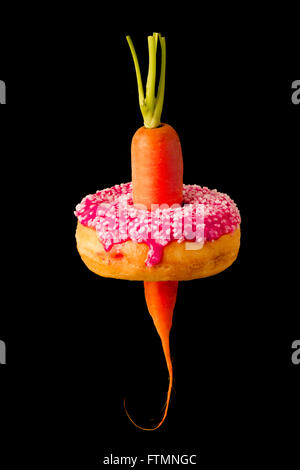 La carota attraverso la ciambella dimostrando una sana versus malsana scelte alimentari e di espandere waistlines / i livelli di obesità. Foto Stock