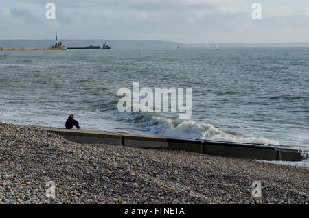 Una donna sola sat contemplando il mare Foto Stock