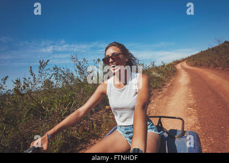 Eccitato giovane donna sulla moto quad. Felice giovane donna alla guida di veicolo fuoristrada in natura. Foto Stock