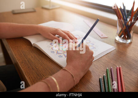 Chiudere l immagine della donna mani disegno in pazienti adulti libro da colorare su un tavolo a casa. Foto Stock