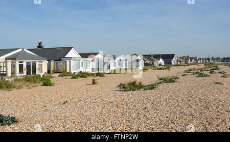 Case sulla spiaggia di ciottoli a Pagham nel West Sussex, in Inghilterra Foto Stock