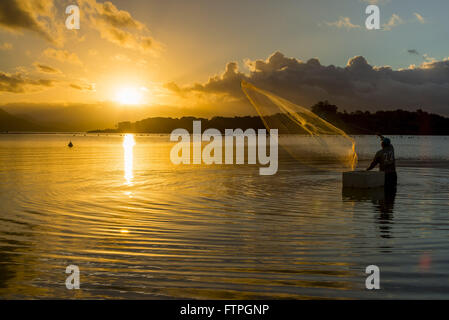 Pescatore di gettare le reti colato al tramonto sulla spiaggia di Ribeirao da Ilha Foto Stock