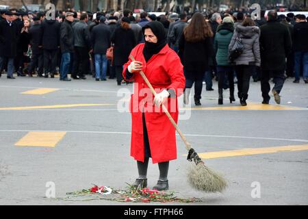 BAKU in Azerbaijan - 20 gennaio 2014 Woman in Red coat spazzando via i garofani rossi Foto Stock