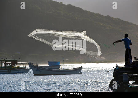 Pescatore getta la sua rete nelle acque della spiaggia di Armacao - il sud dell'isola Foto Stock