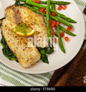 Pesce al forno di filetto con spinaci saltati Foto Stock