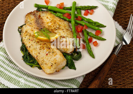 Pesce al forno di filetto con spinaci saltati Foto Stock