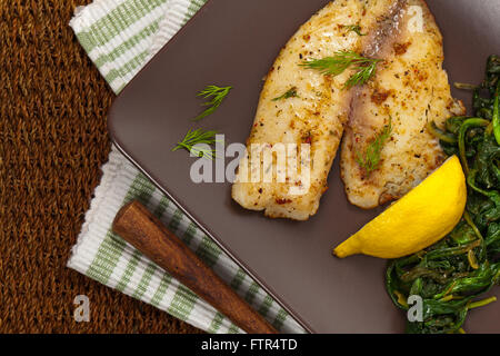 Pesce al forno di filetto con spinaci saltati Foto Stock