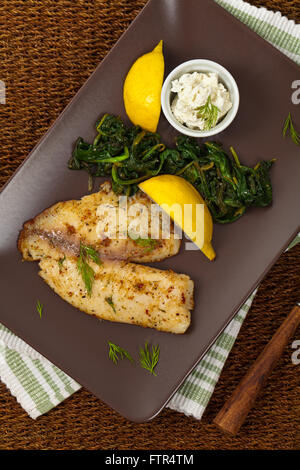 Pesce al forno di filetto con spinaci saltati Foto Stock