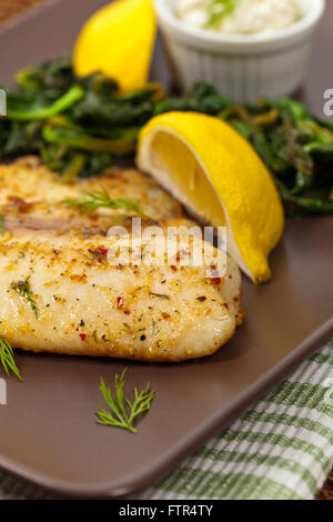 Pesce al forno di filetto con spinaci saltati Foto Stock