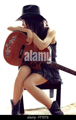 Bruna seduta, in appoggio alla chitarra Foto Stock