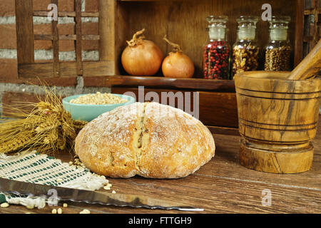 Pagnotta di pane fatto in casa con la cipolla, tutto il frumento, in stile rurale sul muro di mattoni in background Foto Stock