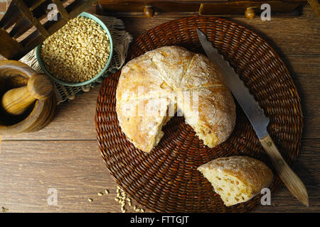 Pagnotta di pane fatto in casa con la cipolla, tutto il frumento, in stile rurale sul muro di mattoni in background Foto Stock